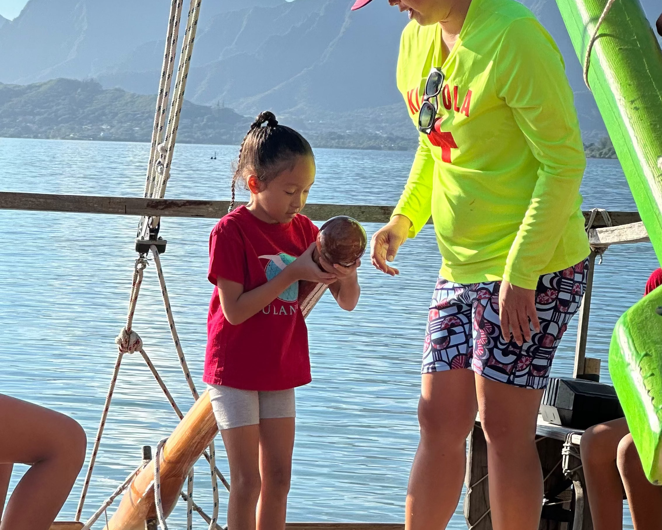 Woman and child on a boat deck with mountains in the background